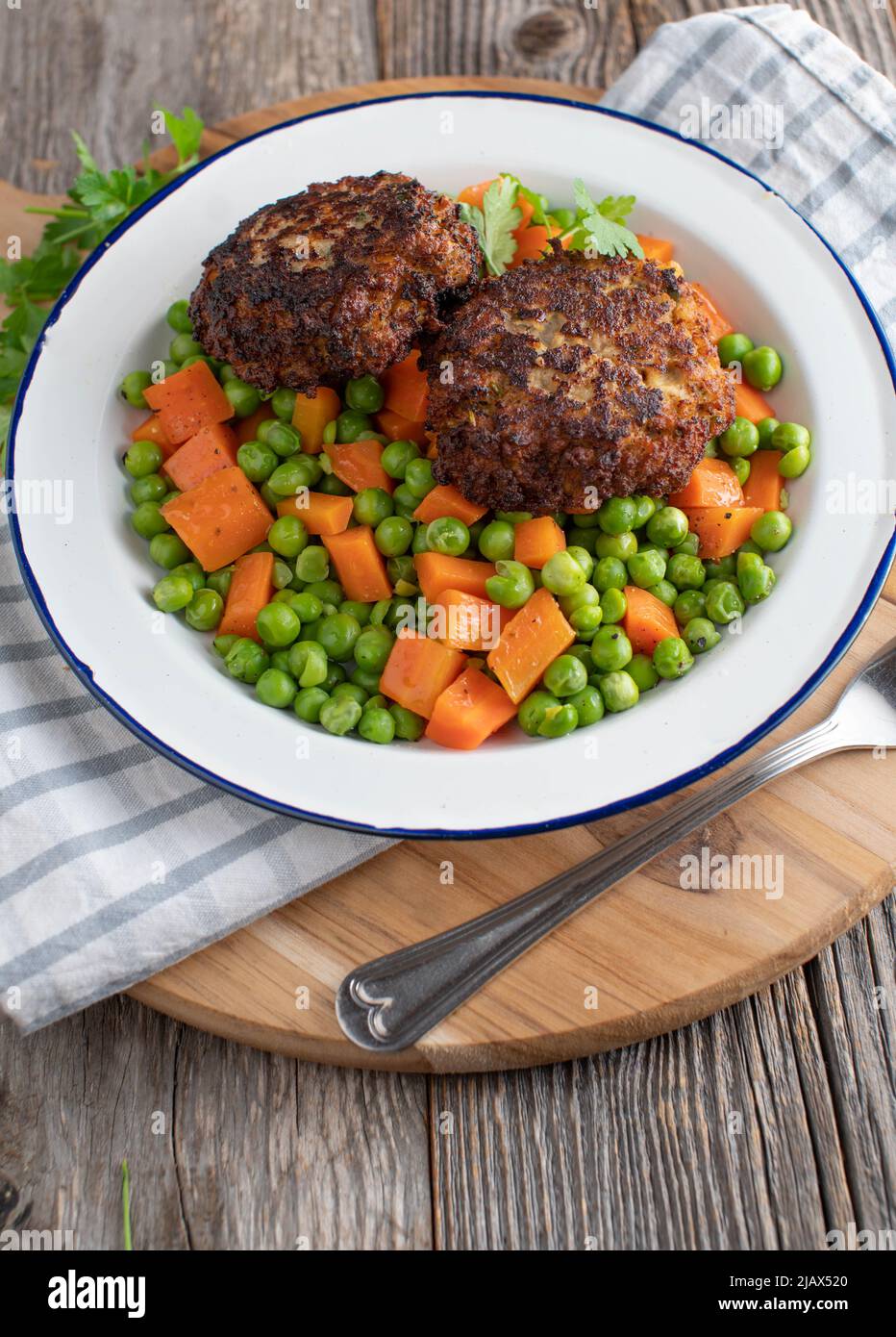 Piselli e carote con polpette di maiale su un piatto. Servita su sfondo rustico e tavolo in legno con spazio per le copie Foto Stock