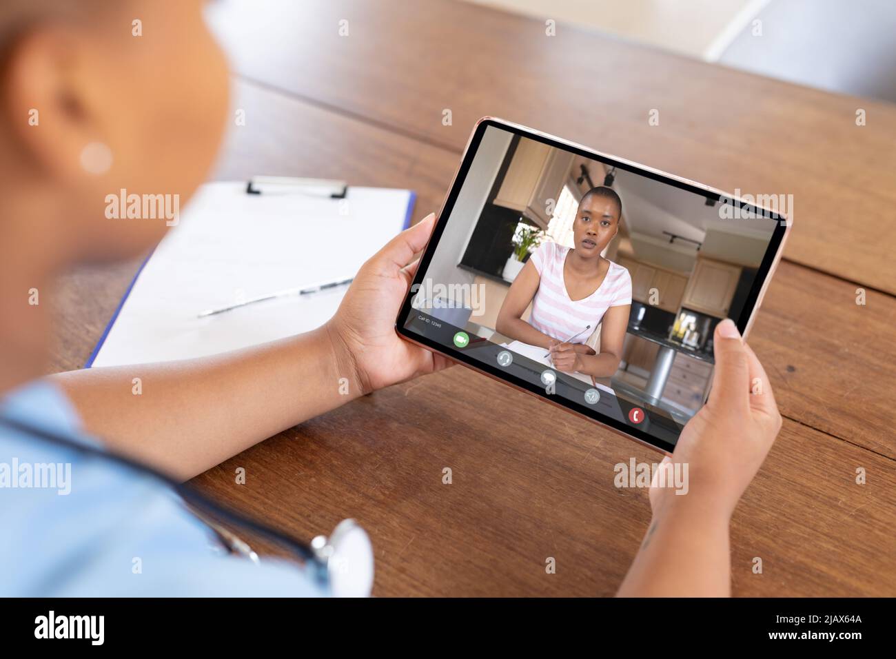 Donna afroamericana che scrive sul libro durante la videochiamata con medico afro-americano Foto Stock
