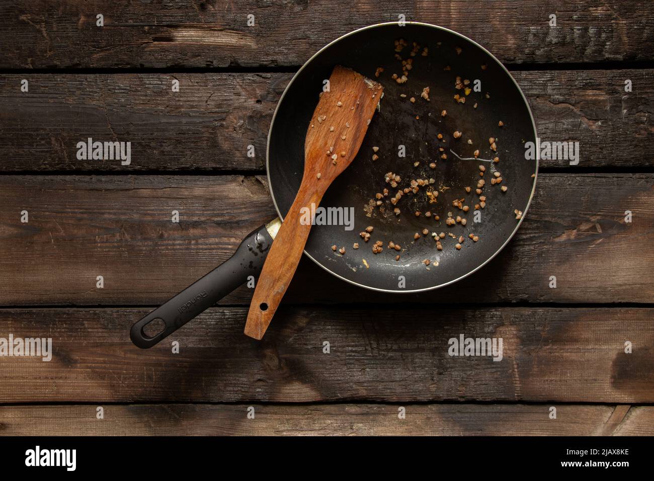 padella sporca dopo aver mangiato su un vecchio tavolo di legno in cucina a casa, utensili da cucina sporchi dopo cena Foto Stock