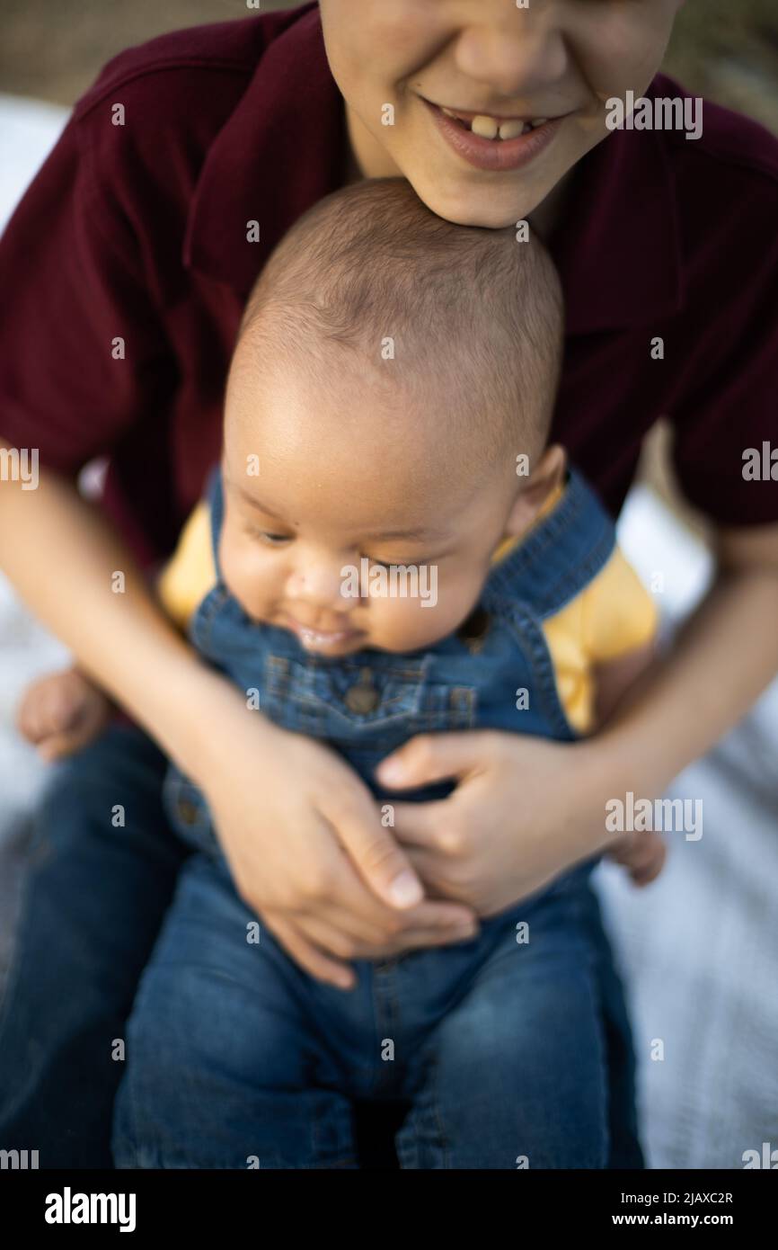 Il bambino più grande sorride tenendo il fratello del bambino e sorridendo Foto Stock