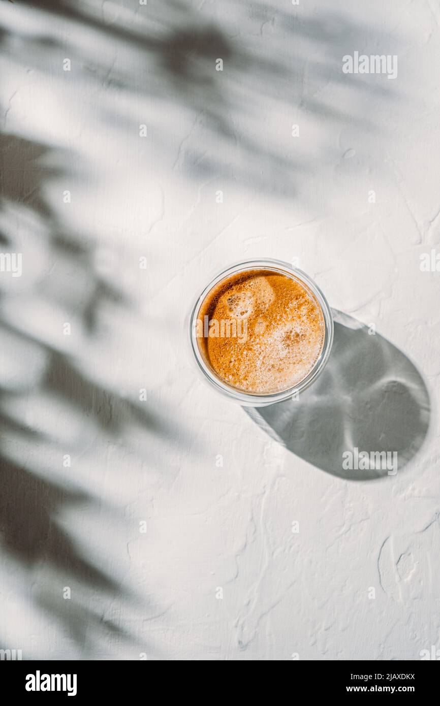 Tazza di caffè sul tavolo bianco con belle ombre Foto Stock