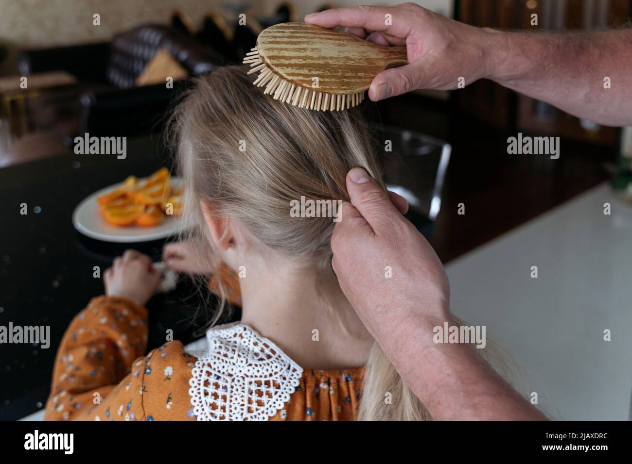 Le mani degli uomini si avvicinano pettinando i capelli della figlia. Foto Stock