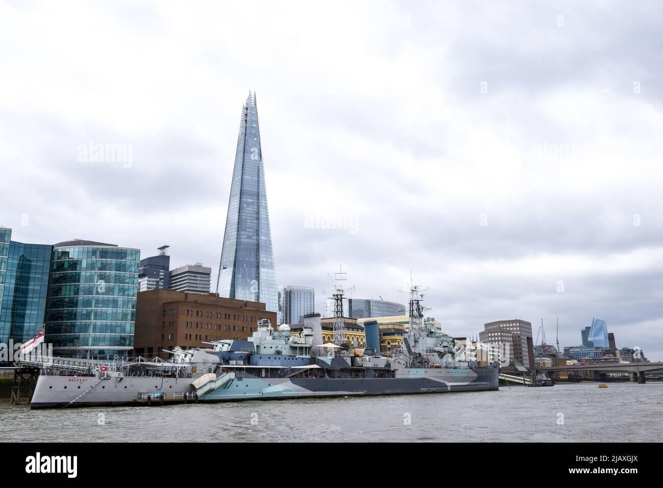 Londra, Inghilterra, Aprile 5 2022 - Vista dal Tamigi dell'HMS Belfast con edifici cittadini sullo sfondo Foto Stock