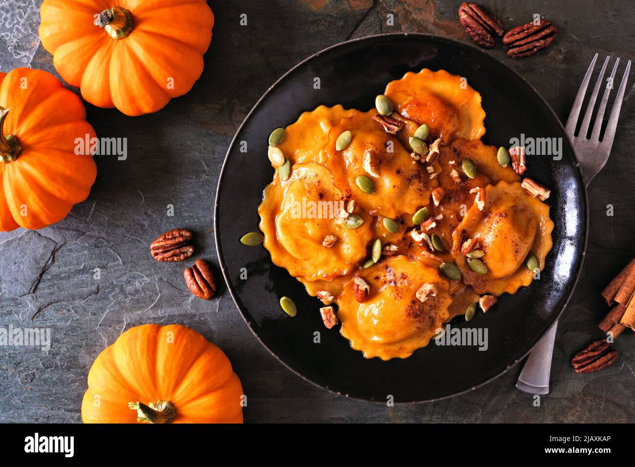 Ravioli ripieni di zucca con noci e semi di zucca. Scena del tavolo, sopra la vista su sfondo scuro. Foto Stock