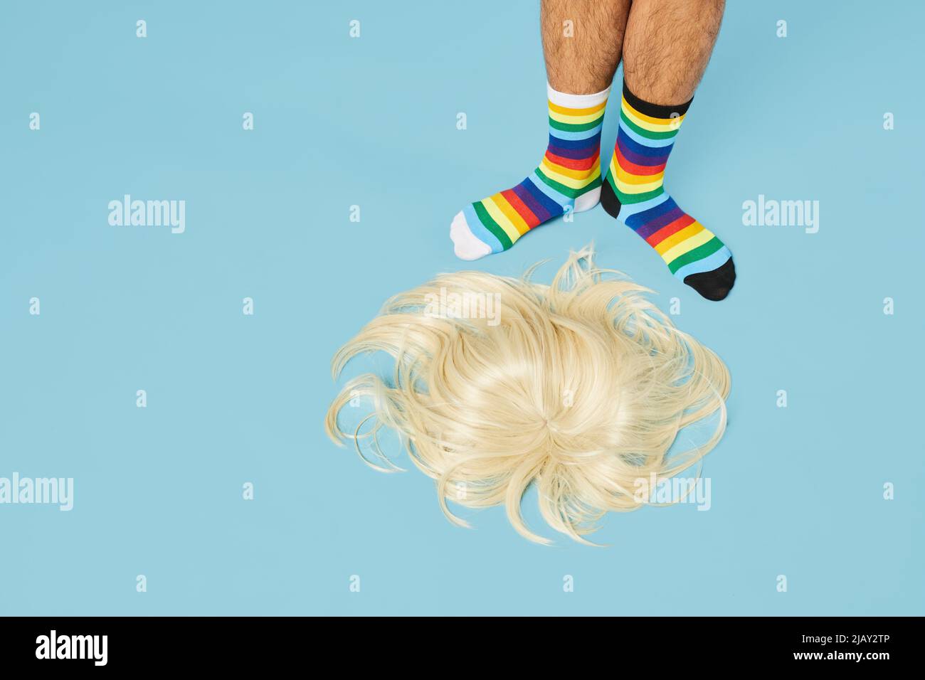 Minimo colpo di uomo indossando calze arcobaleno con bionda sul pavimento su sfondo blu pastello, spazio copia Foto Stock