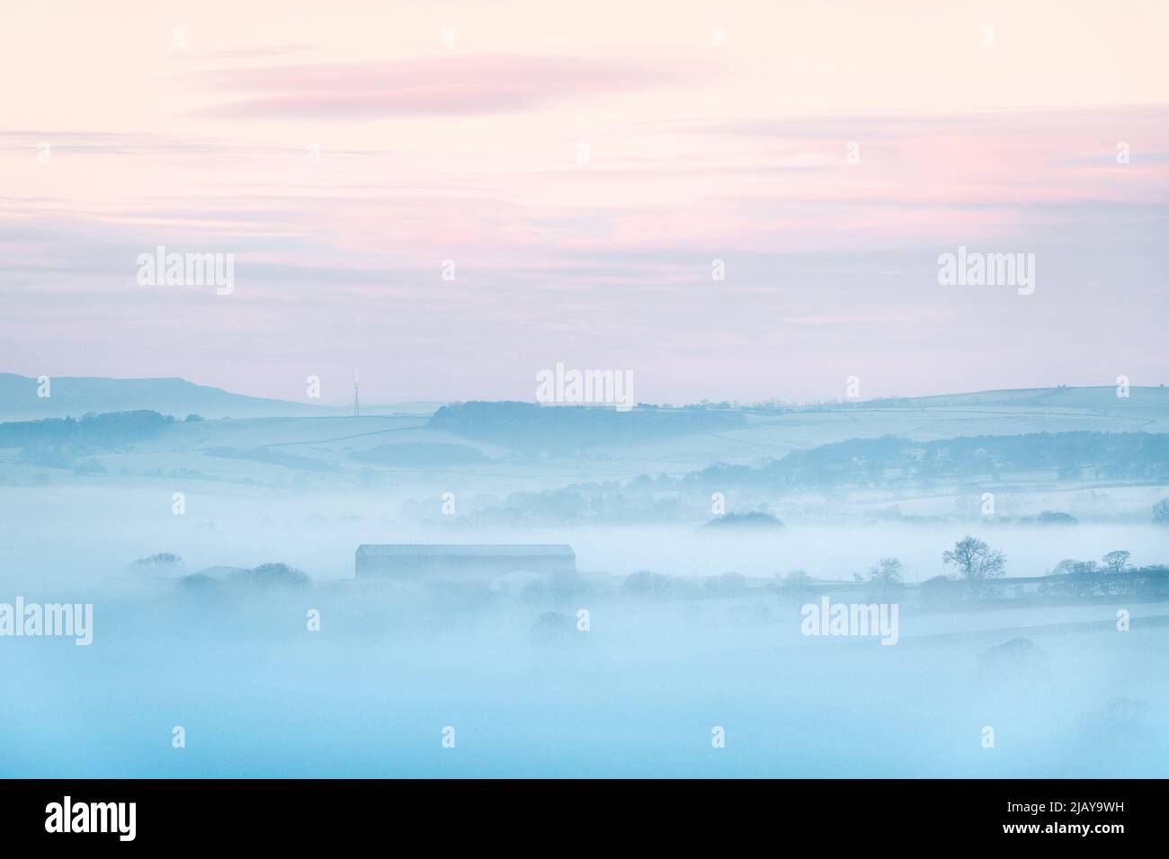 Un grande fienile è brevemente visibile attraverso la nebbia che sgocciola intorno alla valle del Wharfe inferiore su una gelata, mattina d'inverno foggy visto da Almscliffe Crag. Foto Stock