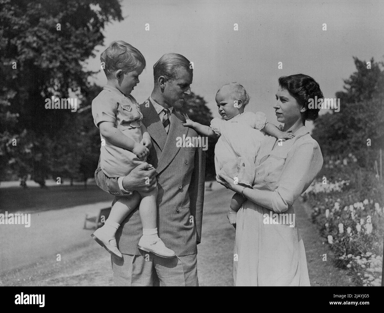 La famiglia felice nel loro giardino -- la principessa Anne, tenuta da sua madre la principessa Elizabeth, sembra volere andare al suo padre il duca di Edimburgo che sta tenendo il principe Charles. Le immagini appena pubblicate mostrano la principessa Elisabetta di H.R.H. ed il duca di Edimburgo con i loro figli il principe Charles e la principessa Anne nel giardino della casa di Clarence House di Londra. Agosto 09, 1951. (Foto di Barratts Photo-Press-Agency). Foto Stock