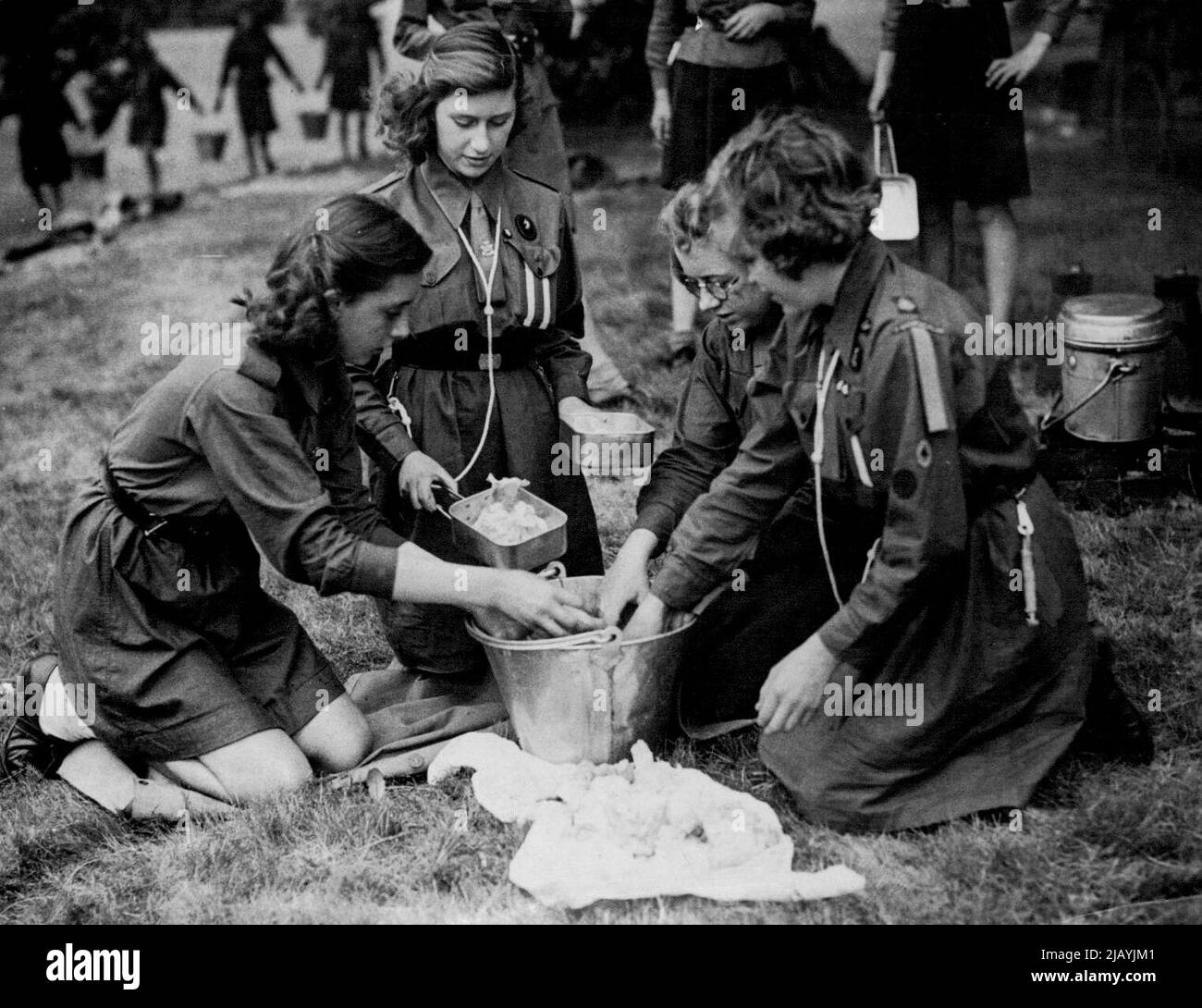 Sea Ranger la Principessa Elisabetta ha trascorso il suo primo giorno come Consigliere di Stato a Camp -- la Principessa Margaret Rose aiuta a preparare un pasto al campo. Le Principesse Elisabetta e Margaret Rose hanno trascorso una giornata in campo con le guide femminili oggi è stato il primo giorno come consigliere di Stato per la principessa Elisabetta durante l'assenza del padre, il re, in visita alle truppe in Italia. Le Principesse hanno preso il loro turno nel contribuire a cucinare i pasti ed a lavare i piatti. Luglio 24, 1944. Foto Stock