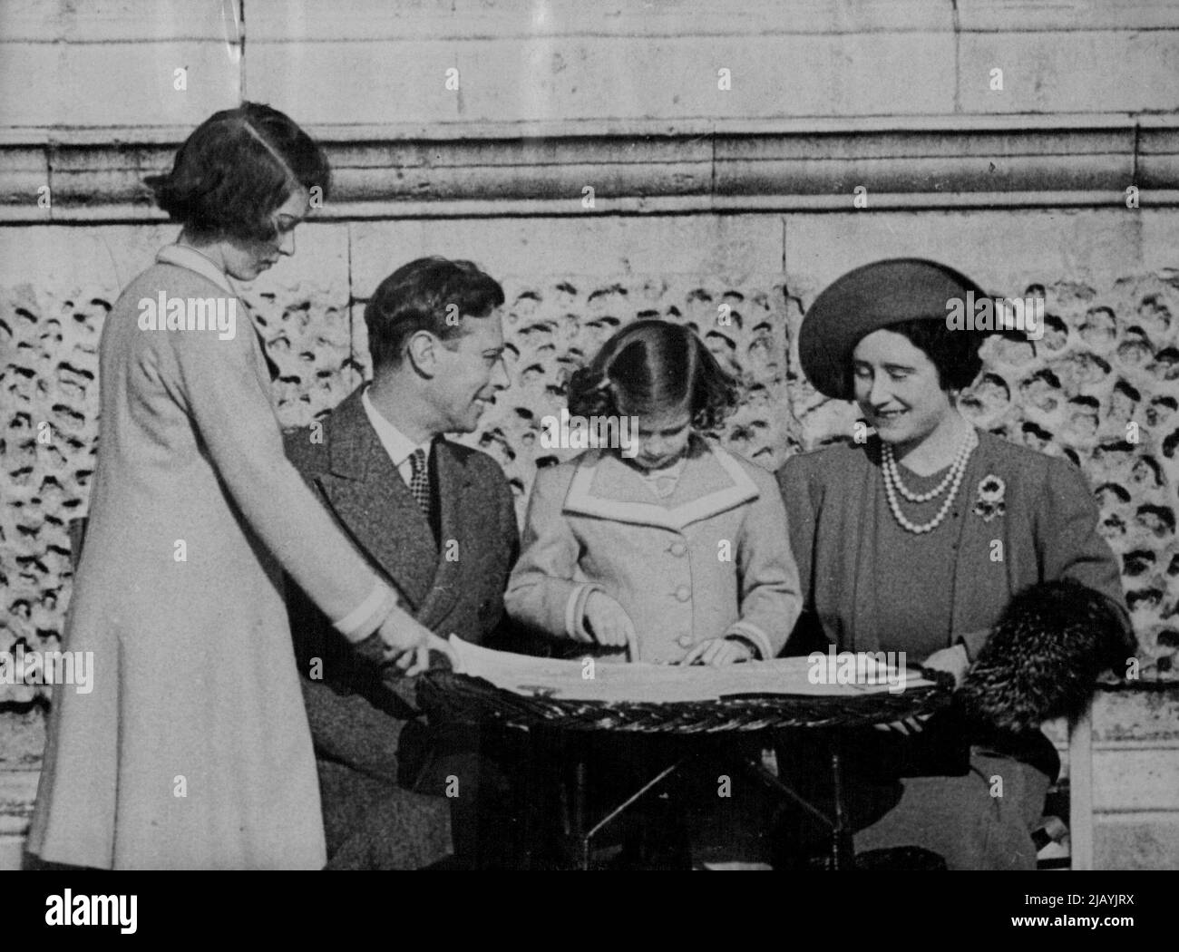 Il Re e la Regina mostrano la loro strada per il Tour Nord America - il Re e la Regina che mostrano il loro percorso per la Principessa Elisabetta (in piedi) e la Principessa Margaret nei giardini del Palazzo. Seduti al sole nei terreni di Buckingham Palace, con una grande mappa che si estende davanti a loro, il Re e la Regina indicarono alla Principessa Elisabetta e alla Principessa Margaret il loro percorso durante la visita in Canada e America il mese prossimo. Aprile 25, 1939. Foto Stock