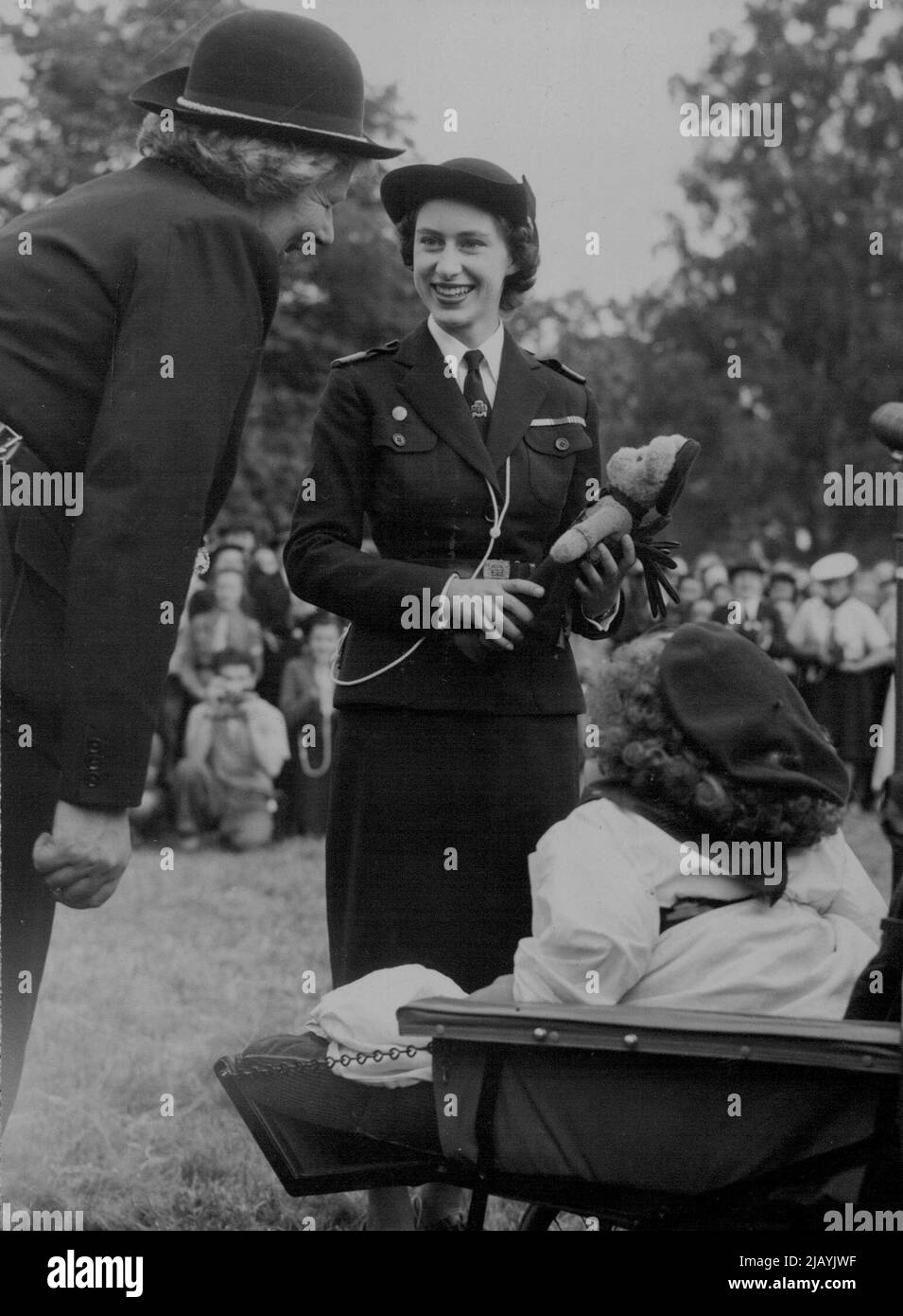 Un 'Teddy' per il Principe Carlo -- sorridendo, la Principessa Margaret accetta un orsacchiotto, fatto per il Principe Carlo, suo nipote, da Ranger Iris Martin (a destra) una guida parata della ragazza. A sinistra c'è la sig.ra Kathleen Daniels, commissario regionale per l'Essex. Sono visti all'Hyland's Park qui vicino, dove la Principessa ha partecipato ad un raduno di 6.000 Girl Guides. Indossa l'uniforme di Sea Ranger Commodore. Giugno 26, 1949. (Foto di Dipartimento pittorico) Foto Stock