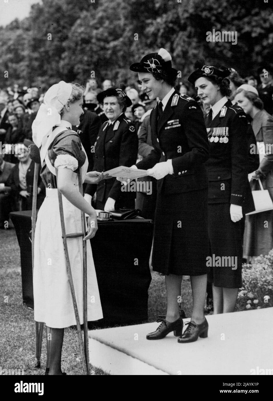 Appoggiata sulla sua crutch, Barbara Goodyear, un cadetto di diciotto anni, riceve un certificato di Brigata Ambulance di San Giovanni dalla sua principessa Margaret, comandante in capo. Barbara, che indossava una scarpa chirurgica, ha rotto la gamba afflitta e ha dovuto scegliere tra totale invalidità - o amputazione, Barbara ha scelto quest'ultima in modo che potesse seguire la sua carriera infermieristica. Il certificato le è stato presentato ieri ad Hyde Park in una sfilata del 7.000 della Brigata St. John Ambulance. Luglio 26, 1954. (Foto di Daily Mirror) Foto Stock