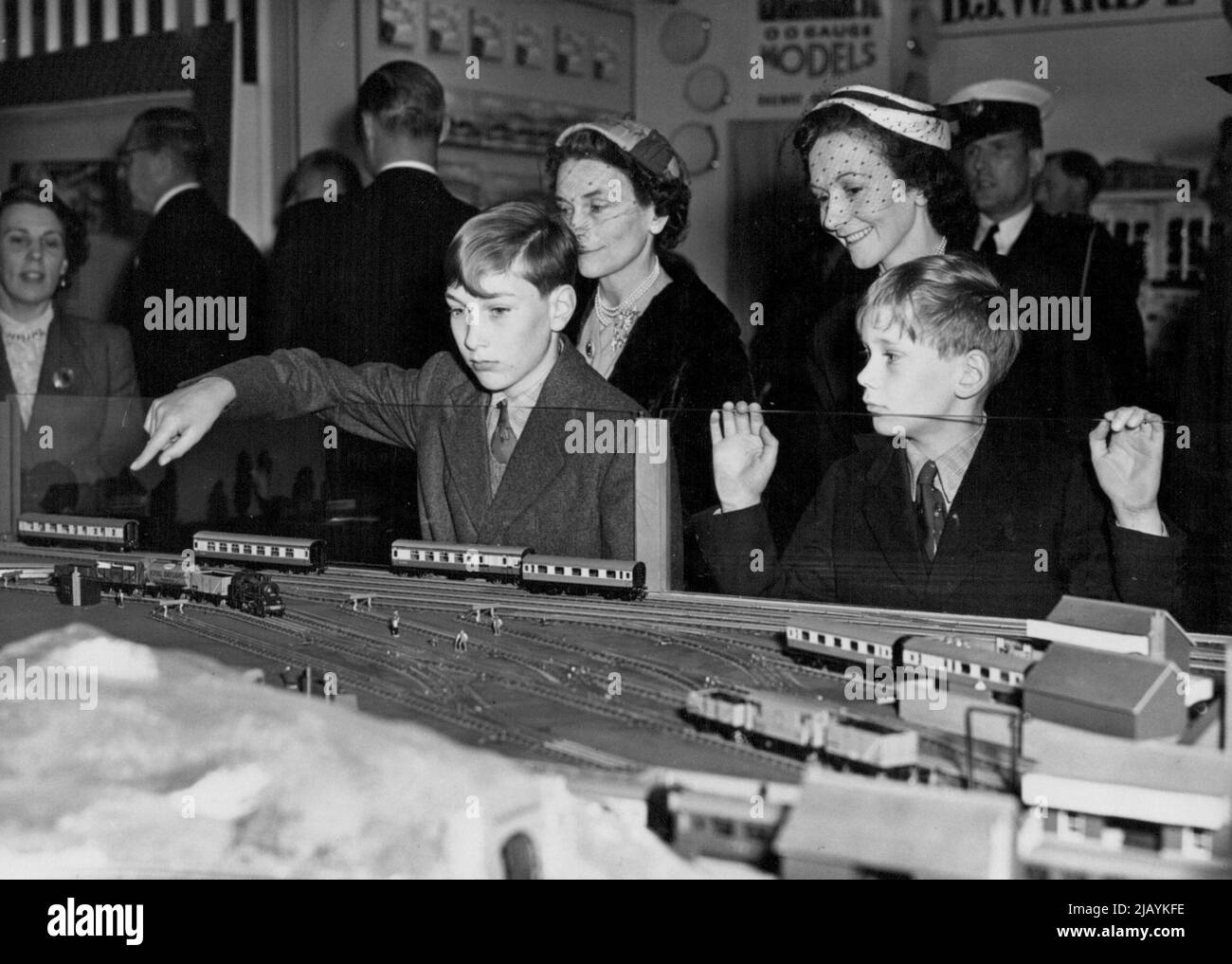 Il Duca e la Duchessa di Gloucester visitano la British Industries Fair: La Duchessa di Gloucester (a sinistra) con i suoi due figli il Principe William (puntando) e il Principe Richard, interessati alla ferrovia in miniatura vista oggi al B.I.F. Il Duca e la Duchessa di Gloucester e i loro due figli, oggi hanno fatto visita alla British Industries Fair, a Londra. Maggio 05, 1954. (Foto di Fox Photos). Foto Stock