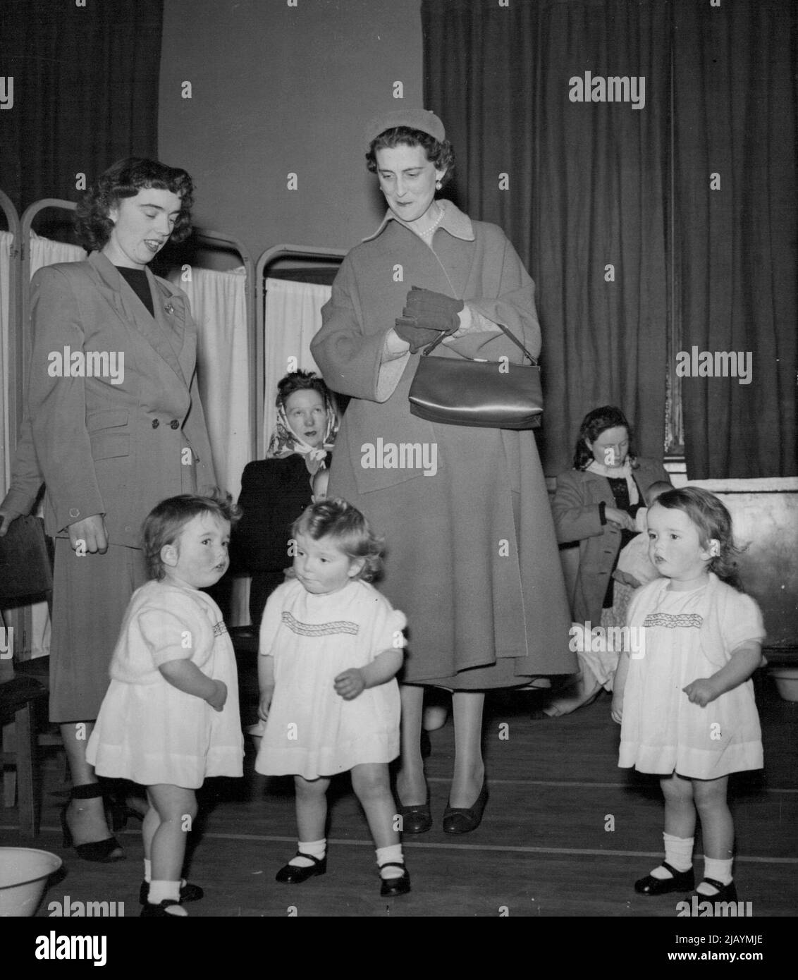 La duchessa del Kent incontra i tripli - la duchessa del Kent in una visita a Slough, Bucks., oggi (Lunedi) - incontra le triplette di Slough, Elizabeth, Keren e Susan Stuart. La duchessa indossa un berretto simile a un piattino e un cappotto morbido e avvolgente con maniche di puff. Durante la sua visita di oggi, ha visto il Centro della Comunità di Slough, l'unità di radiografia di massa (X-Ray) e l'infermiera dei bambini in Farnham Road. Febbraio 26, 1951. (Foto di Reuterphoto). Foto Stock