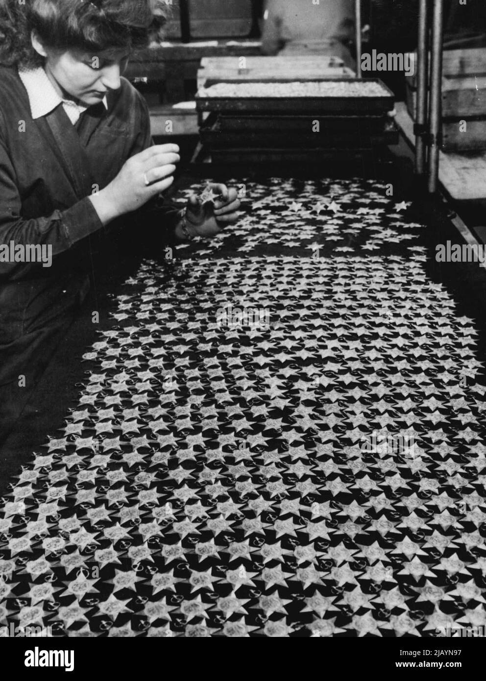 Medaglie per gli eroi di guerra della Gran Bretagna -- Una ragazza lavoratori esamina una delle molte medaglie britanniche della campagna appena coniato nella zecca reale a Londra il marzo 13. Le medaglie a forma di stella, che saranno rivelate dalle migliaia, saranno assegnate agli eroi britannici della campagna in Africa, Birmania, Italia, Francia, Germania, L'Atlantico e il Pacifico e le battaglie aeree sull'Europa. Marzo 16, 1946. (Foto di stampa associata). Foto Stock