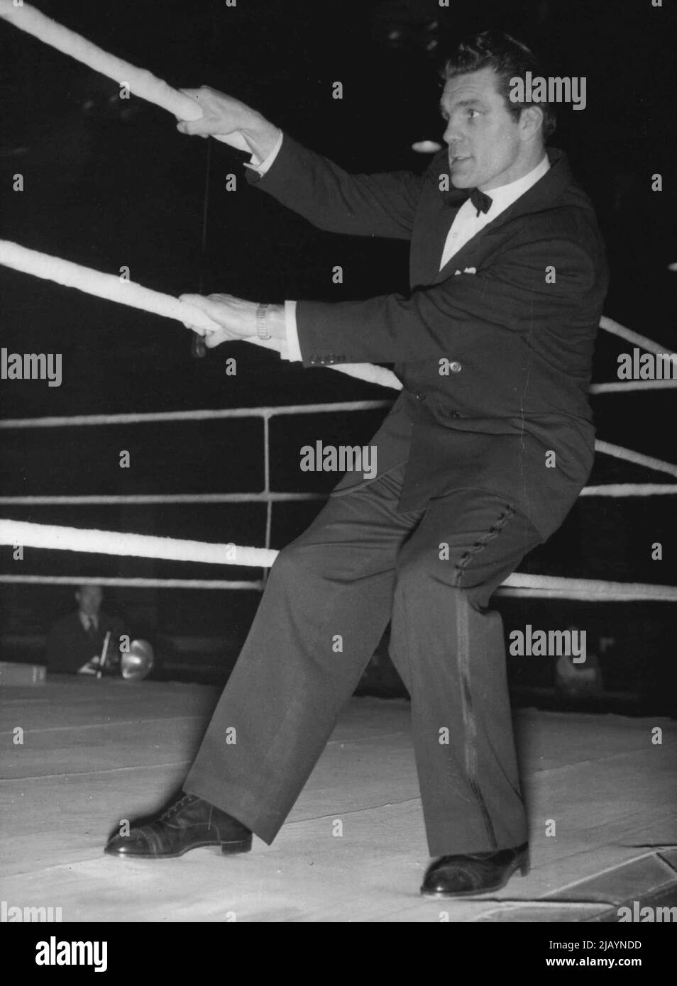 All'esterno guardando dentro -- Freddie, così spesso all'interno delle corde, dà loro un rimorchiatore dall'esterno per testare il loro tratto prima dei concorsi, marzo 25. Freddie Mills, ex campione mondiale di pesi massimi, ha organizzato la sua prima fattura presso la sala dell'imperatrice di Londra la sera del 25 marzo. Nel terzo round del principale bout Yolande Pompee, leggero pesantissimo da Trinidad, Knoked out danese leggero pesantissimo campione Erik Jensen. Aprile 24, 1952. (Foto di Rota Pictures) Foto Stock