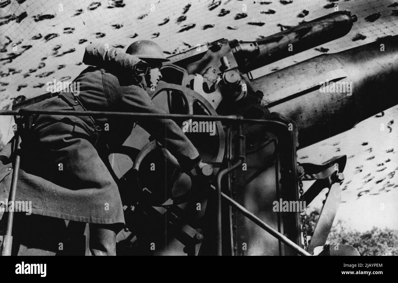 All'allerta: Sotto una rete di mimetizzazione, un soldato britannico eleva un Howitzer montato su una ferrovia da 12 pollici durante le recenti manovre. Questo tipo di pistola spara un guscio del peso di circa un terzo di una tonnellata. Marzo 16, 1941. (Foto di stampa associata). Foto Stock