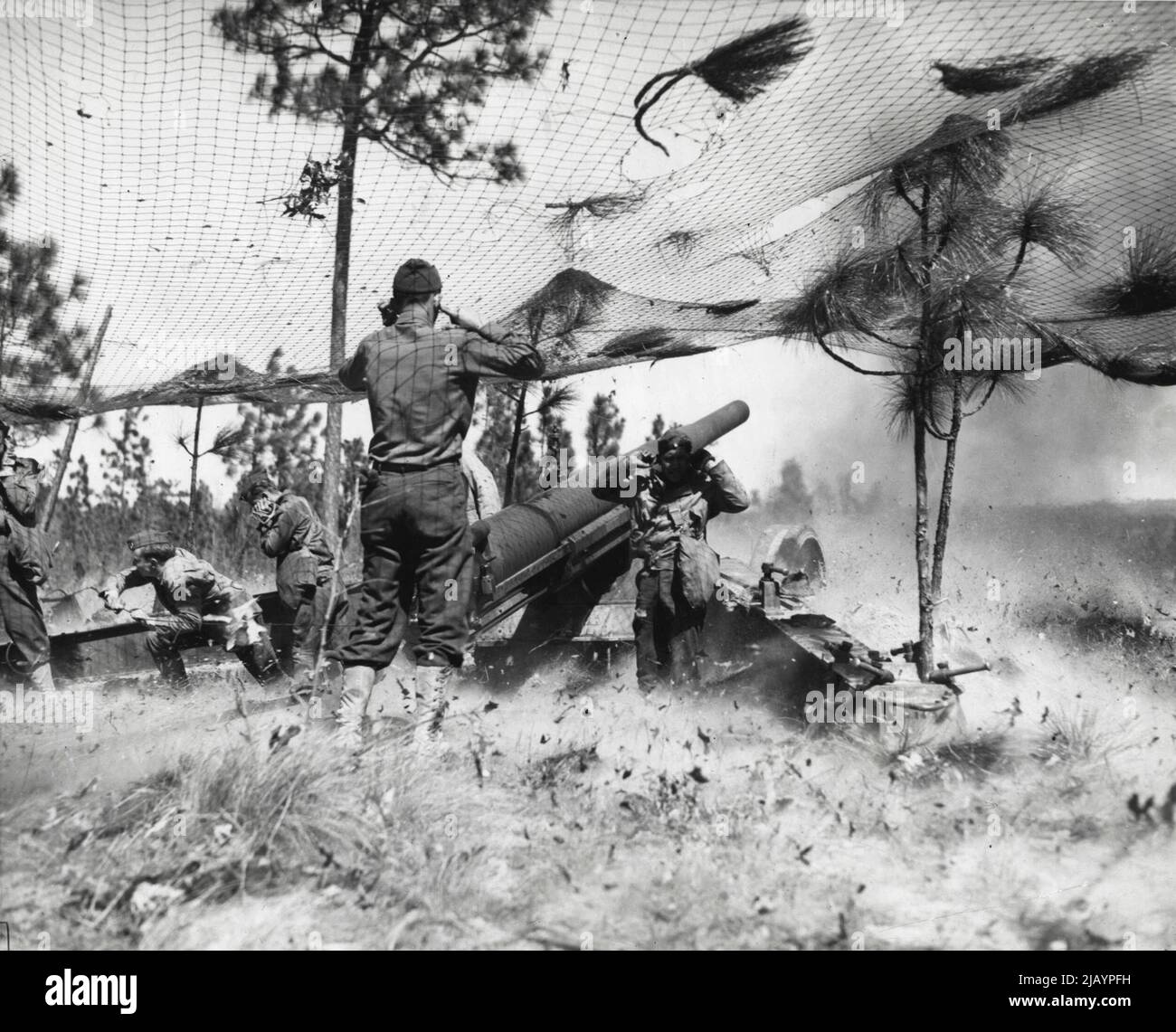 Le esplosioni di fucili a lungo raggio a Target: I soldati dell'artiglieria da campo 36th a Fort Bragg, N. C., arrestano le loro orecchie dopo lo scarico del 155mm. Fucile, il campo più lungo piede in uso da parte dell'esercito degli Stati Uniti. Sotto la sua rete di mimetizzazione, il fucile del 155mm può colpire bersagli a 17 miglia di distanza. Marzo 29, 1942. (Foto di stampa associata). Foto Stock