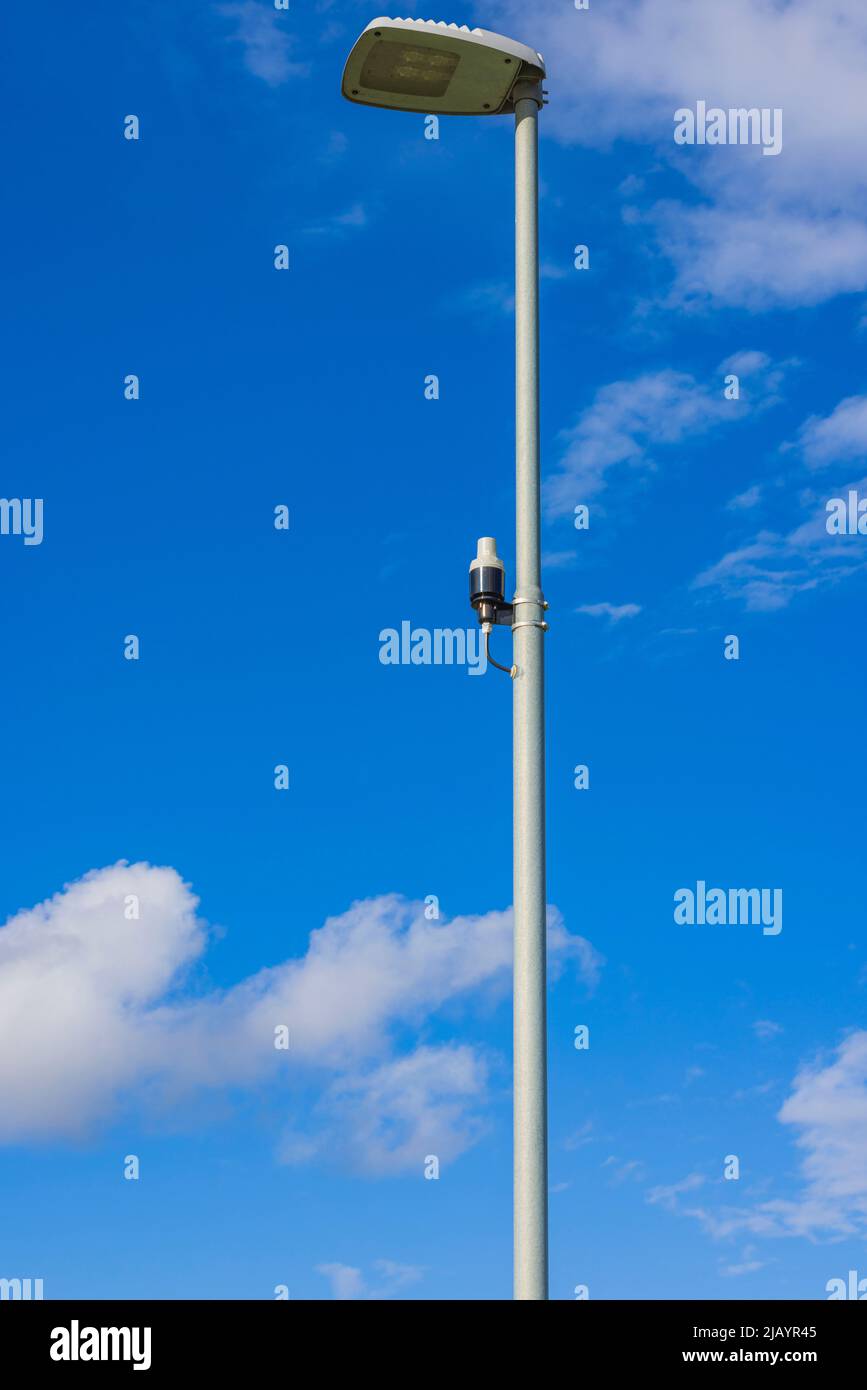 Vista ravvicinata del sensore di luce sul palo di illuminazione stradale sul cielo blu con rare nuvole bianche sullo sfondo. Svezia. Foto Stock
