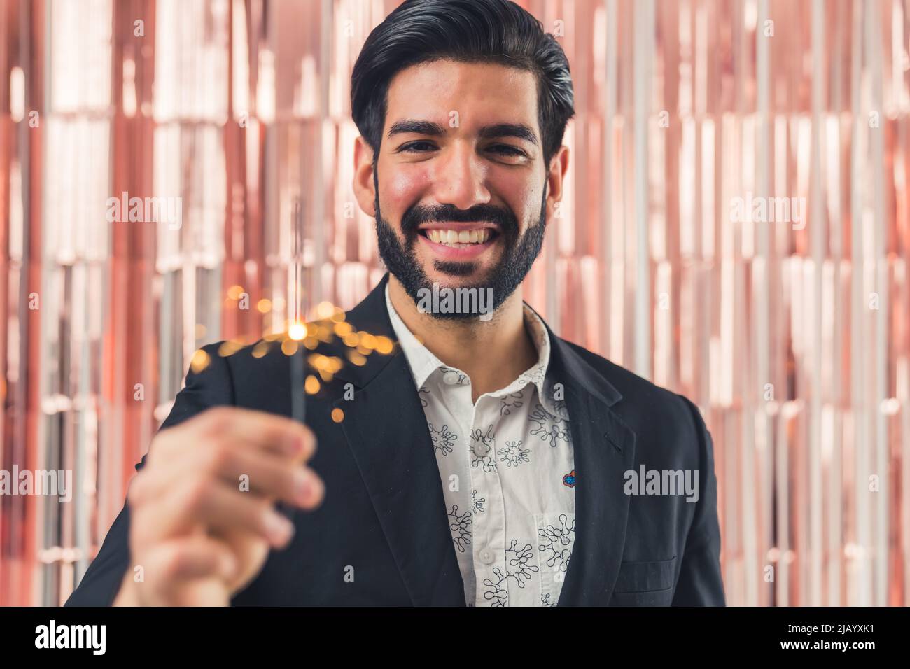 Gioioso lating americano maschio tenendo bengala luce in mano sorridente fotocamera, festa in ufficio. Foto di alta qualità Foto Stock