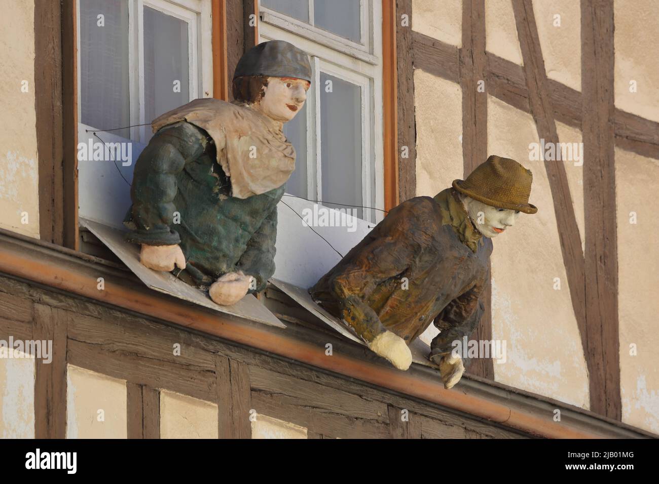 Due sculture a grandezza naturale che sporgono da una finestra a Mühlhausen, Turingia, Germania Foto Stock
