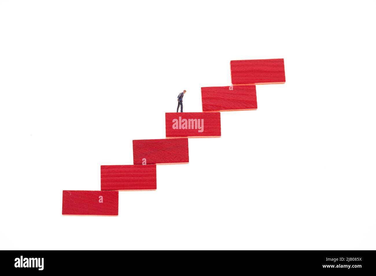 Concetto di crescita professionale. Figura di un uomo d'affari su una scala rossa isolata su sfondo bianco Foto Stock