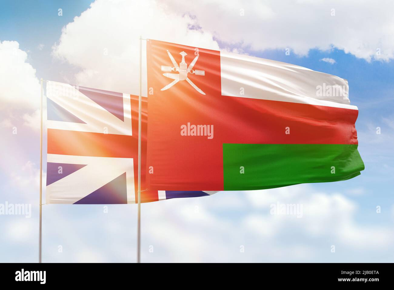 Cielo azzurro soleggiato e bandiere di oman e Gran bretagna Foto Stock