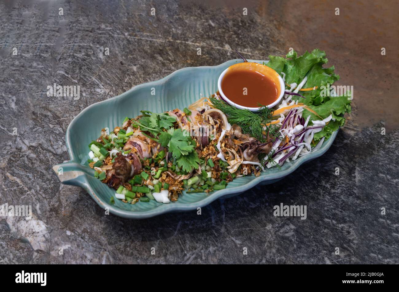 Calamari ripieni di trita di maiale e aglio cospargere di aneto, coriandre e cipolla primaverile servita con salsa al peperoncino. Messa a fuoco selettiva. Foto Stock