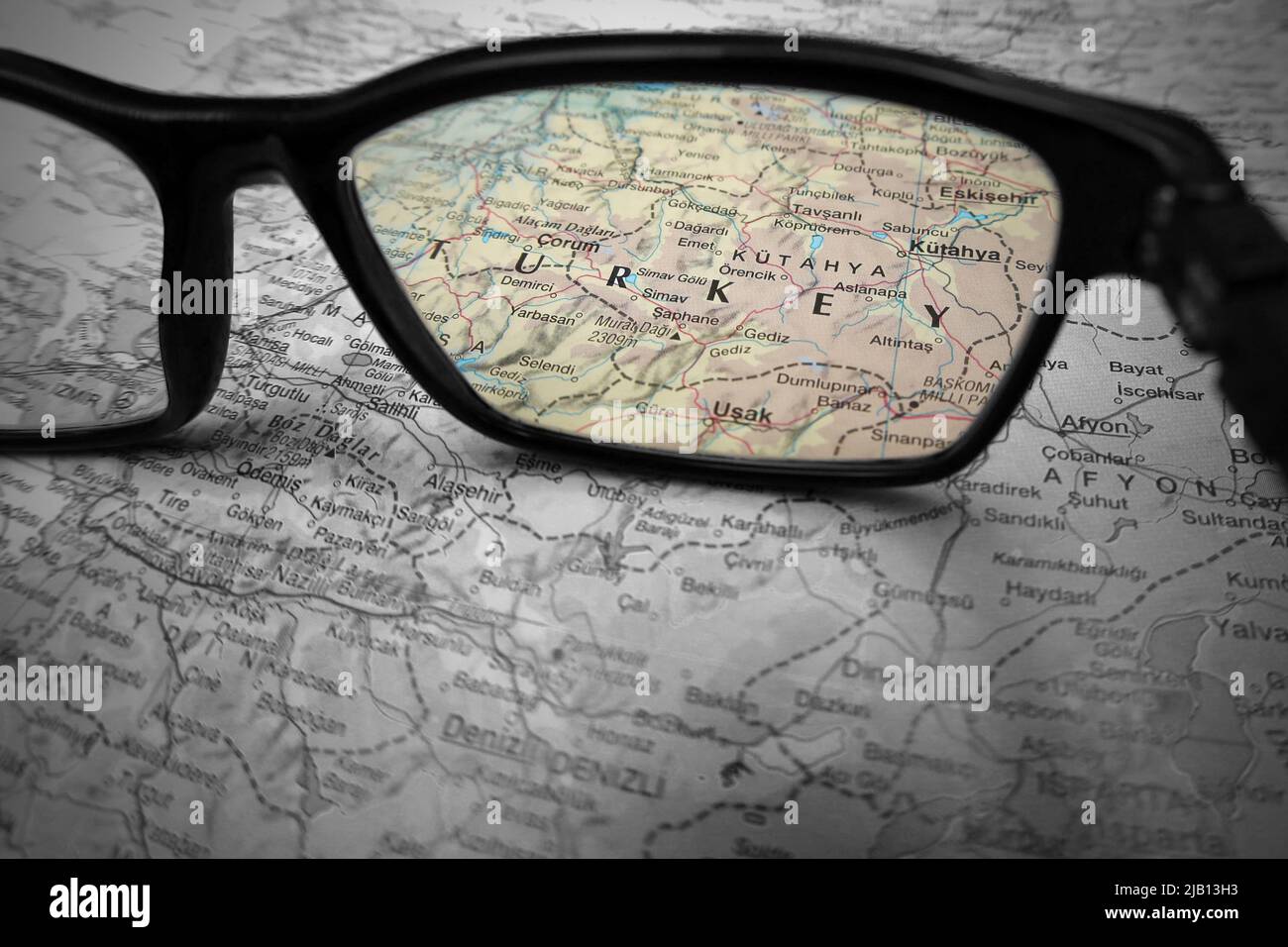Un'immagine creativa illustrativa che mostra il paese della Turchia su una mappa attraverso l'obiettivo di occhiali da lettura. La parola turchia a colori con il resto bla Foto Stock