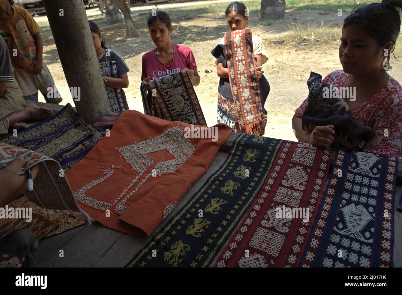 Le donne che portano tessuti tradizionali Sumbanesi da vendere ai visitatori nel villaggio tradizionale di Umabara a Watu Hadang, Umalulu, Sumba orientale, Nusa Tenggara orientale, Indonesia. Foto Stock