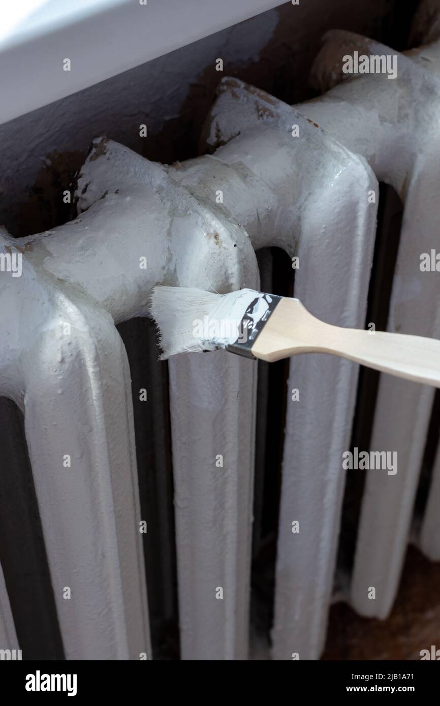 Verniciatura dei radiatori con una spazzola speciale. Verniciatura della batteria. Foto Stock