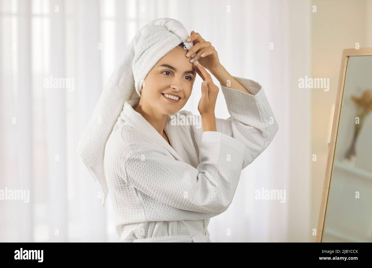 Felice bella giovane donna che fa massaggio facciale rilassante o esercizi di yoga del viso Foto Stock