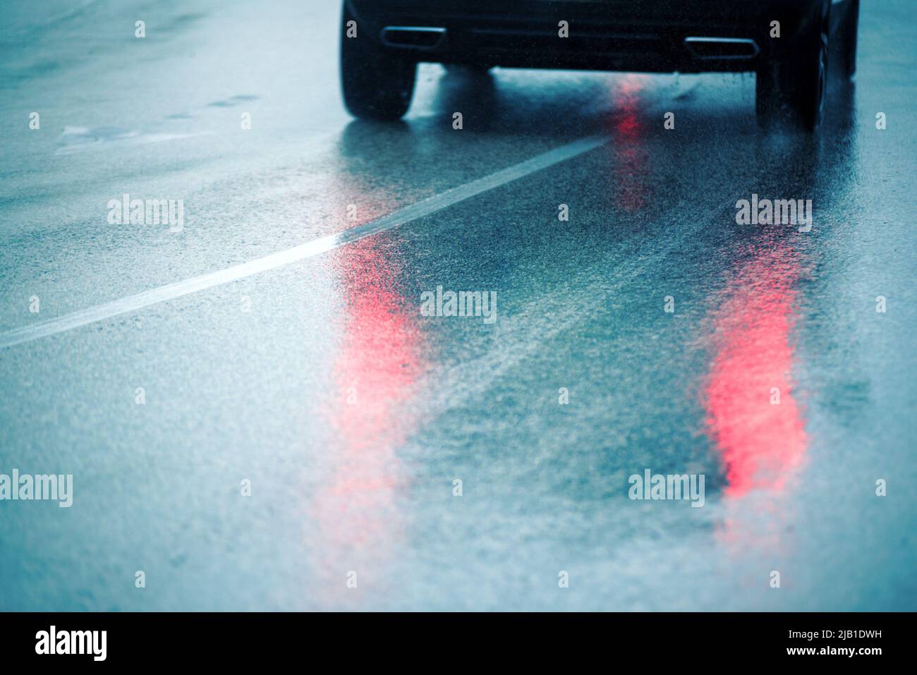 Il riflesso delle luci in movimento dell'auto sull'asfalto bagnato Foto Stock