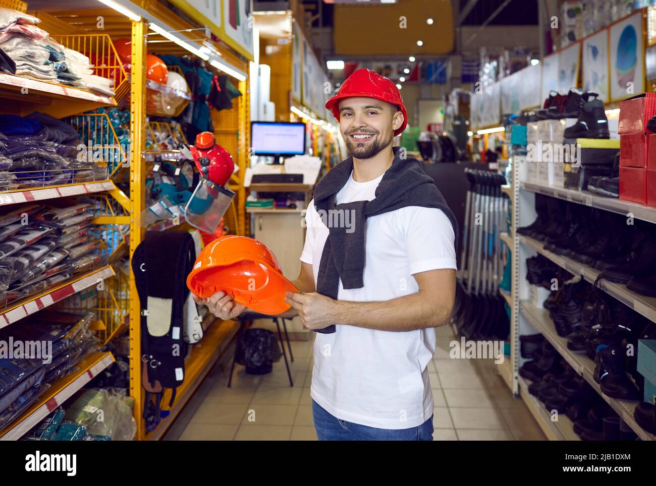 L'uomo durante lo shopping sceglie l'elmetto protettivo nell'ipermercato dei materiali da costruzione. Foto Stock