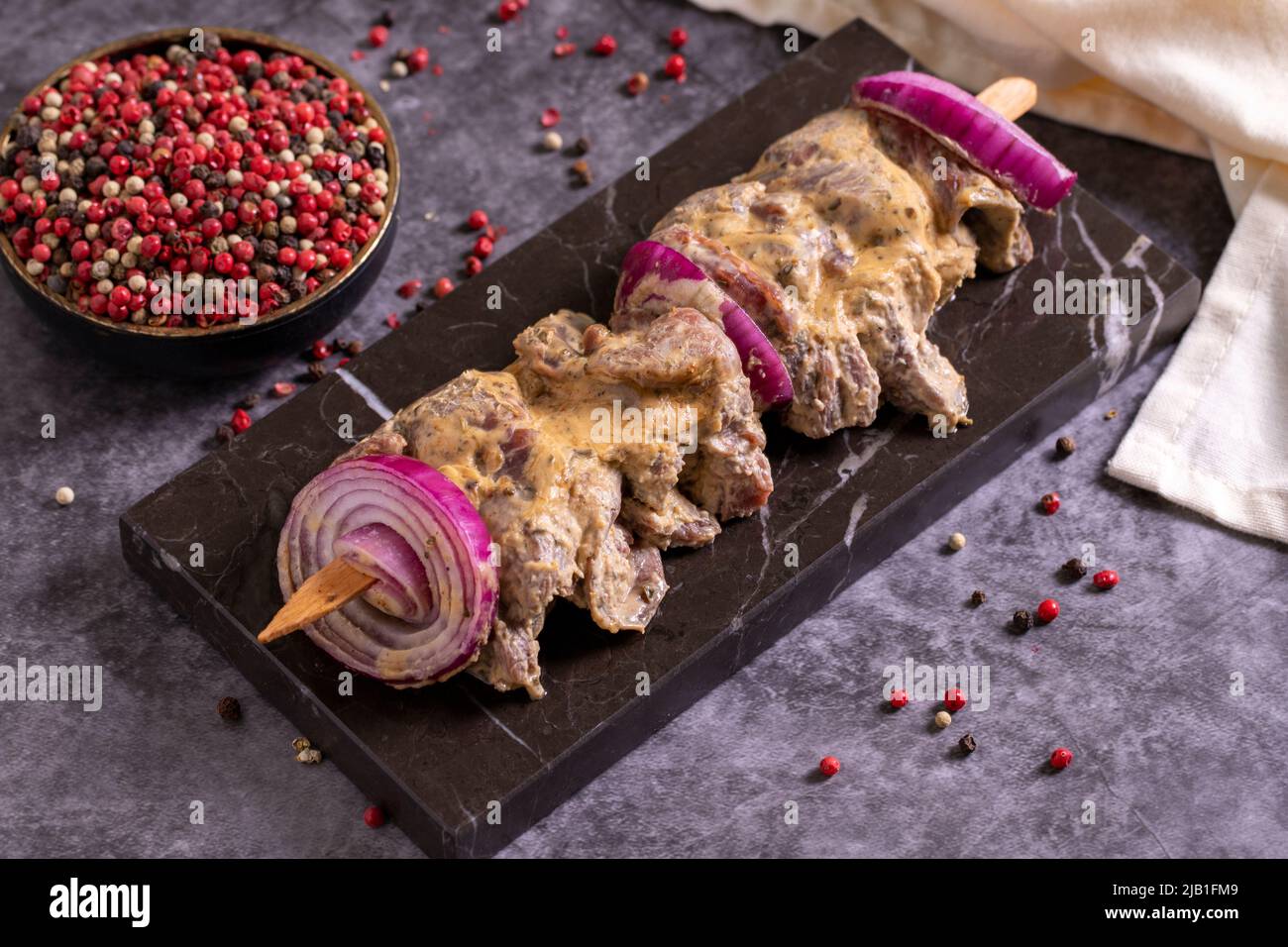 Kebab shashlik su sfondo scuro. Kebab di saslik crudo fresco con spezie. Primo piano Foto Stock