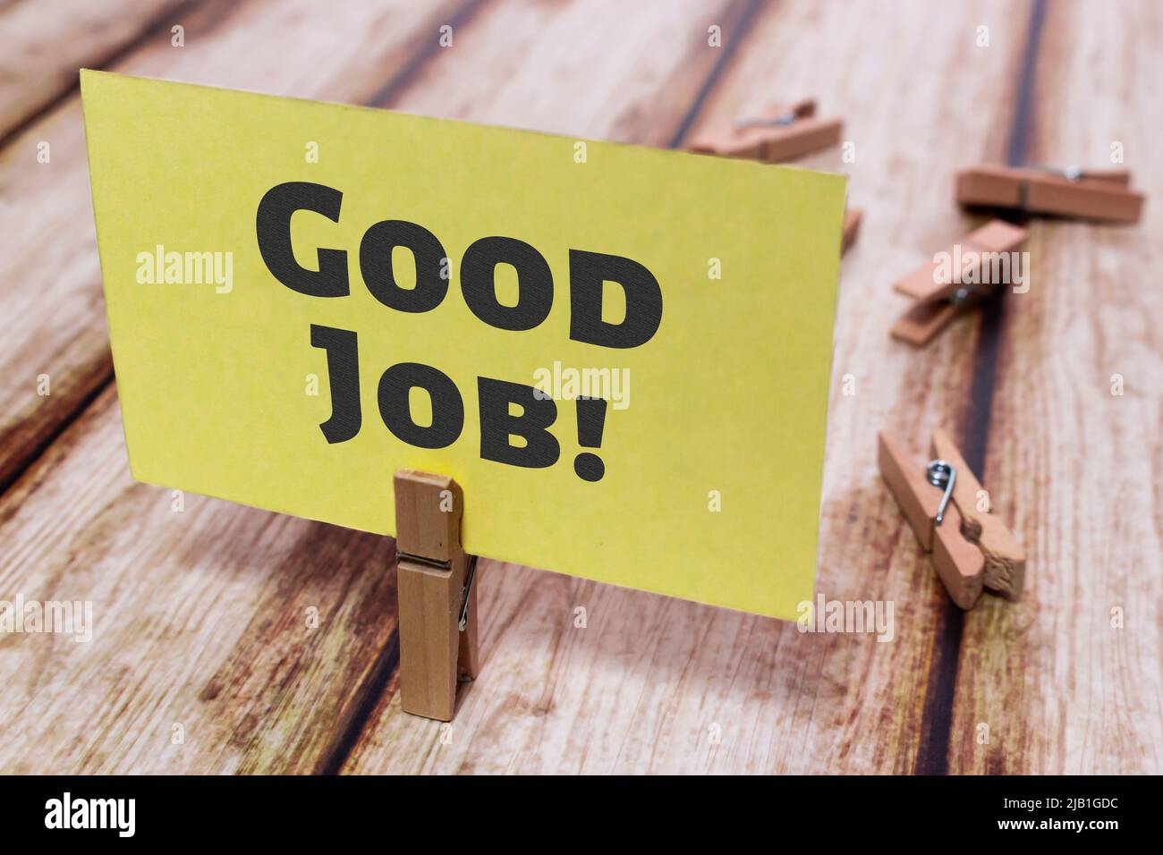 La scheda messaggi mostra un buon lavoro! su un elegante tavolo shabby. Pinch in legno naturale che tiene la nota di carta gialla. Business, attività personale e il concetto di risultato del lavoro Foto Stock