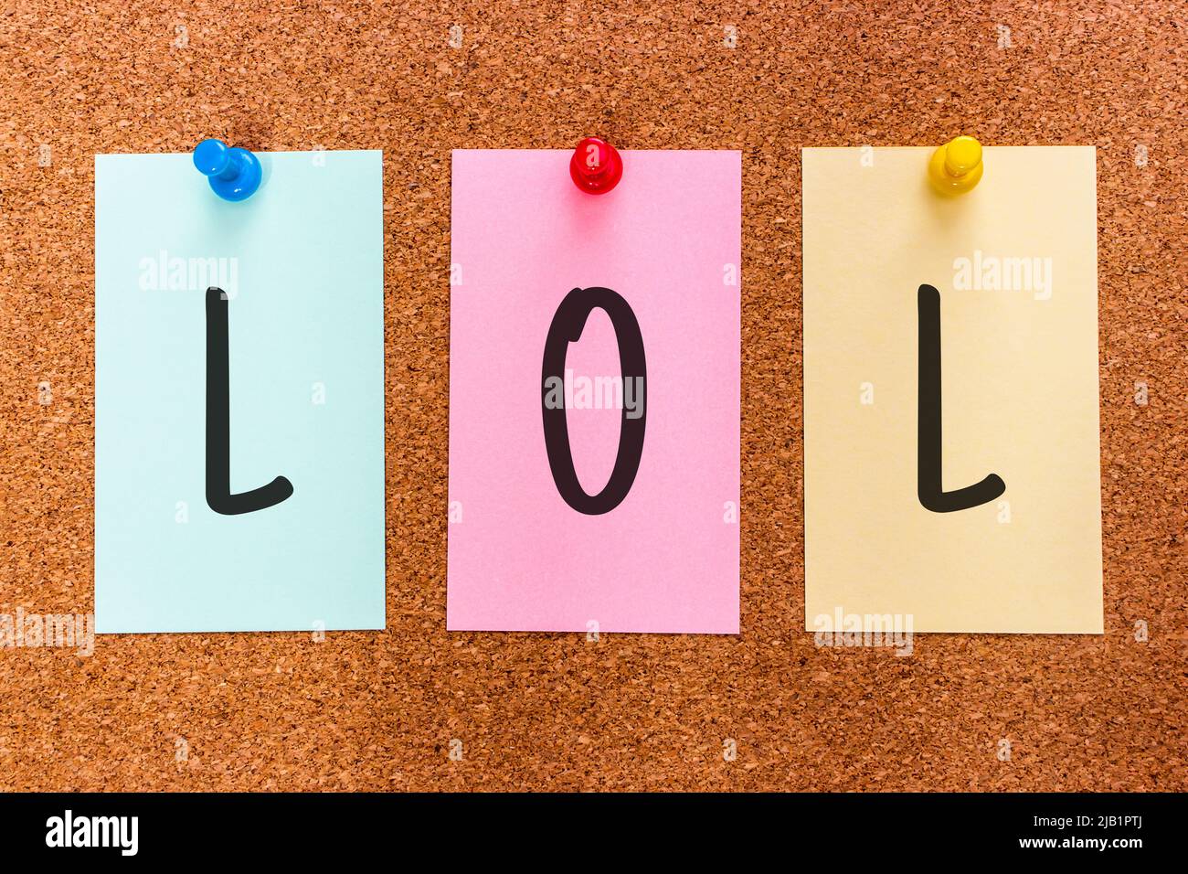 3 lettere parola chiave LOL (ridendo fuori forte), un elemento popolare dello slang del Internet, sugli adesivi multicolore fissati ad un bordo di sughero. Foto Stock