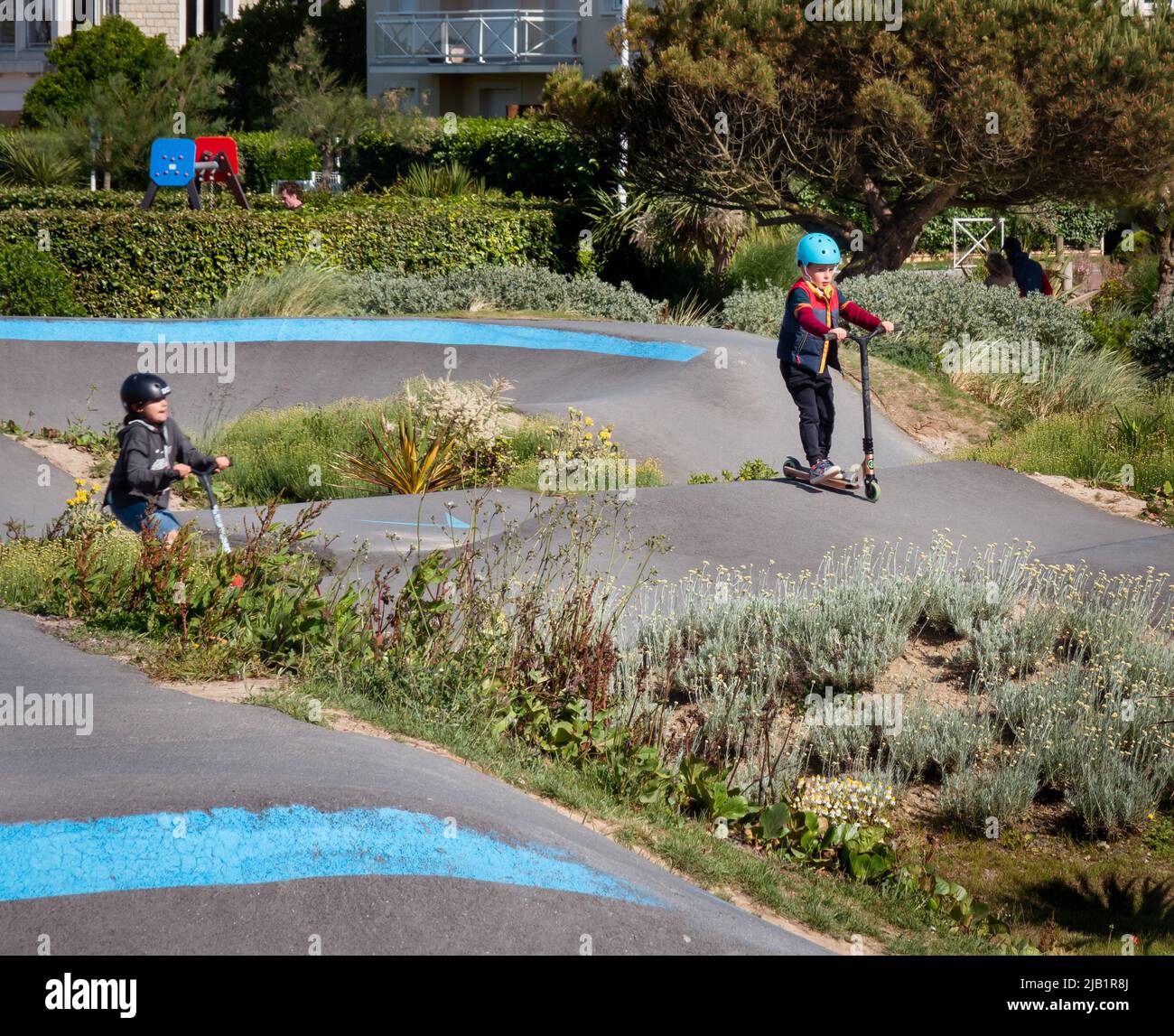 Merville, Francia maggio 2022. Bambini che indossano caschi scooter su una pista sportiva in una giornata di sole, vacanze estive Foto Stock