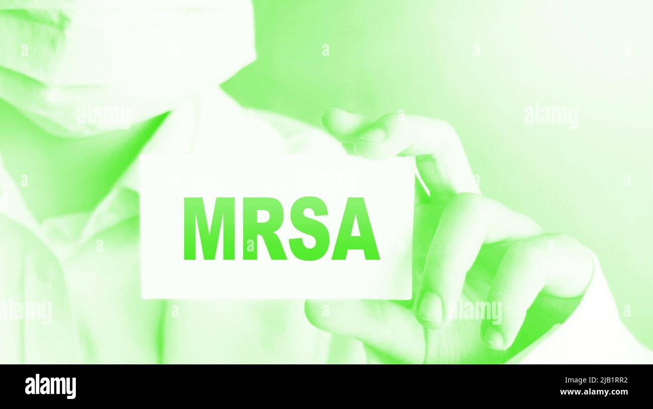 Medico, indossare maschera di protezione del viso mostra una scheda con il testo MRSA. Concetto medico. Foto Stock