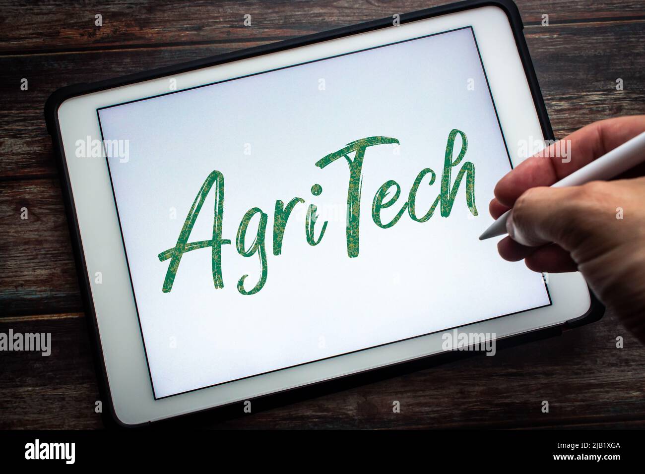 Parola chiave Agritech (tecnologia agricola) su tablet. Concetto di tecnologia in agricoltura. Uomo che tiene la penna stilo wireless Foto Stock