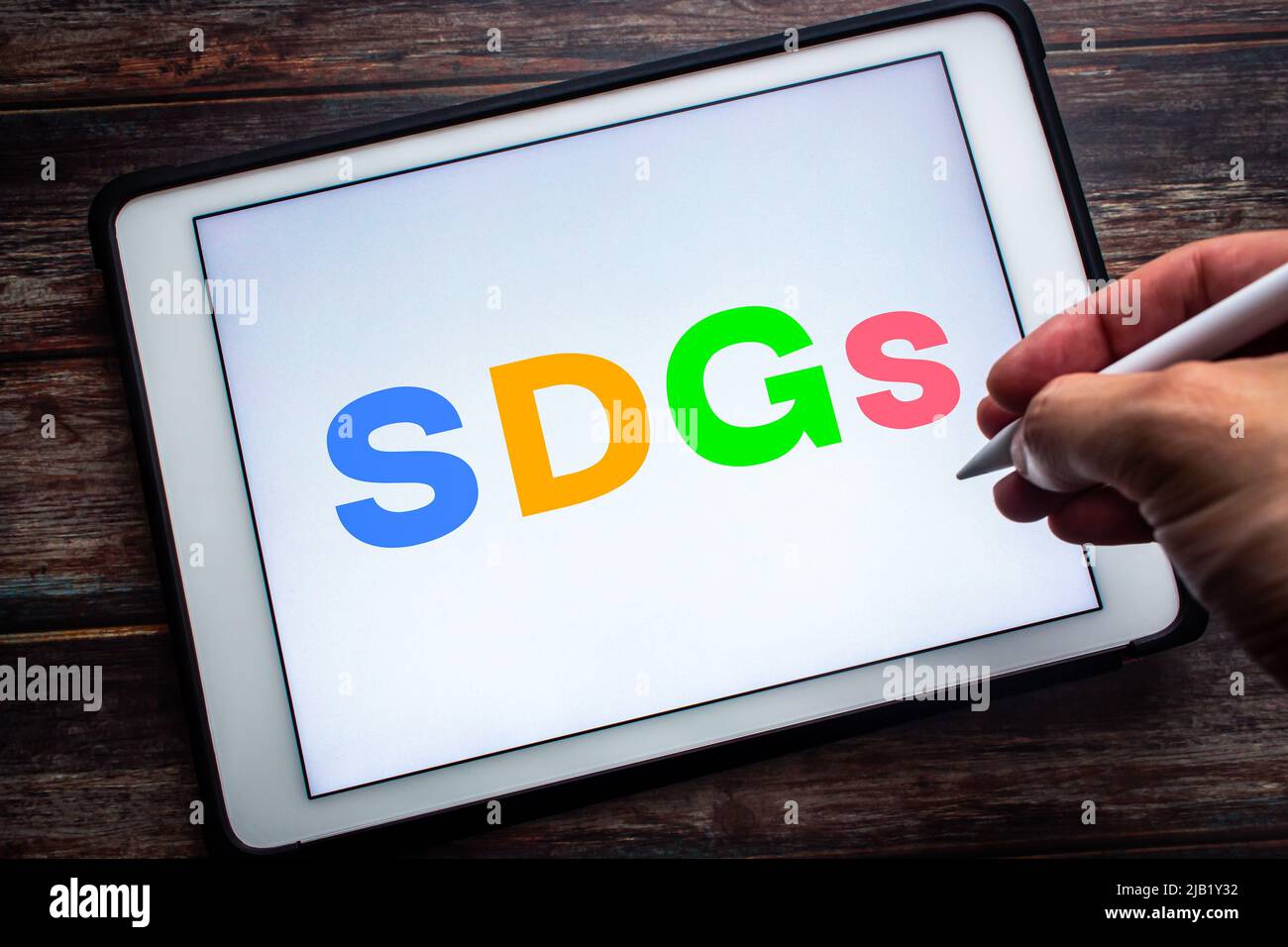 Primo piano parola chiave SDG (obiettivi di sviluppo sostenibile) su tablet. Concetto di obiettivi globali per un futuro migliore per tutti. Uomo che tiene la penna stilo wireless Foto Stock