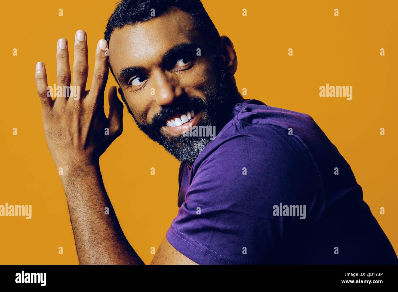 primo piano ritratto di un bel giovane uomo adulto sensibile che balla con t-shirt viola su uno studio di sfondo giallo Foto Stock