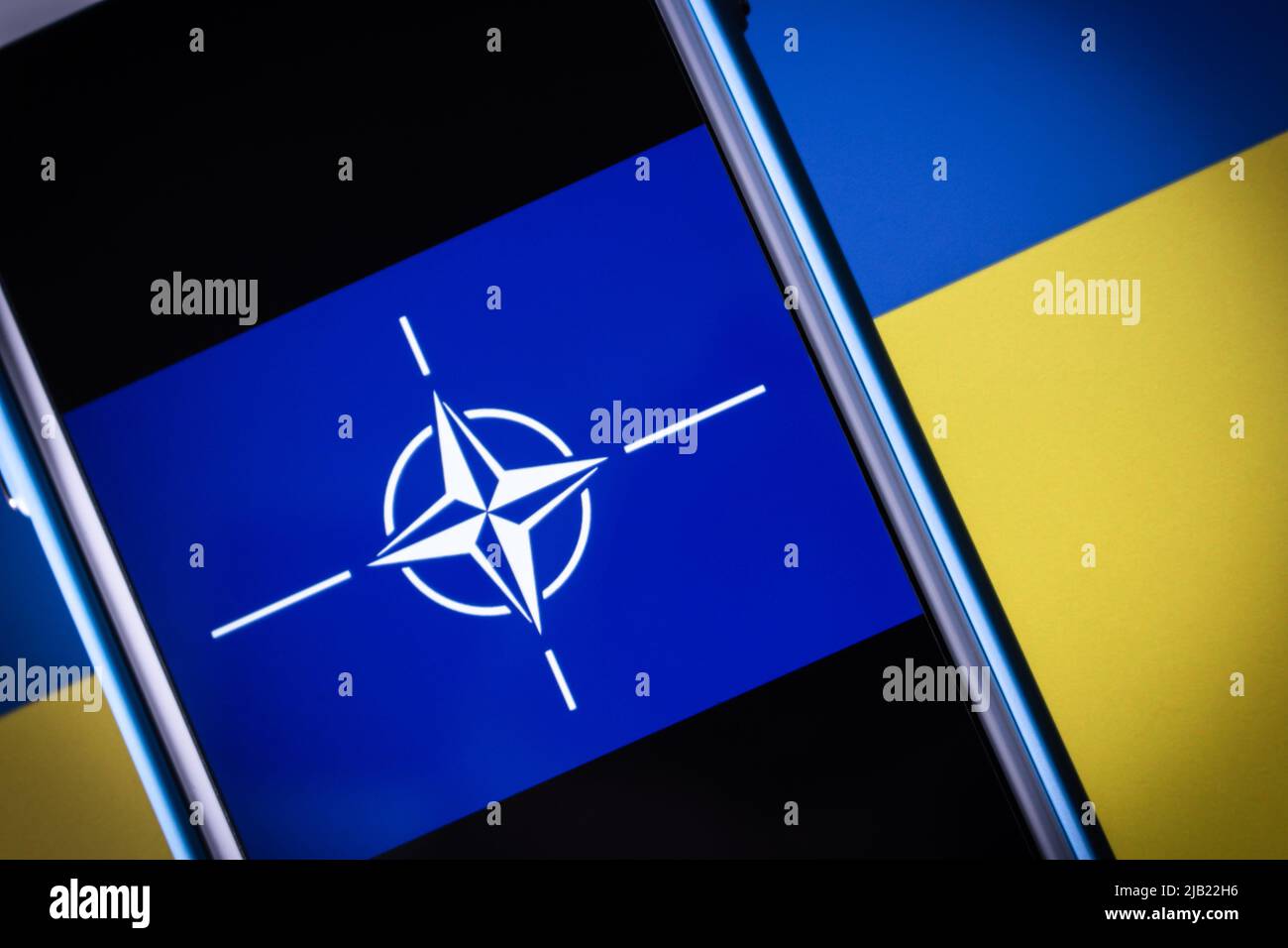 Logo della NATO (l'Organizzazione del Trattato del Nord Atlantico, OTAN in francese), sulla bandiera Ucraina in un clima oscuro. La NATO è un'alleanza militare intergovernativa Foto Stock