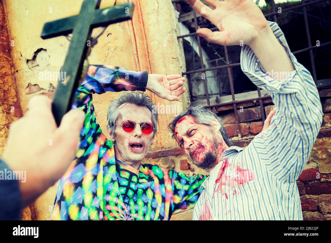 esorcismo con un crocifisso su due zombie nel cimitero Foto Stock