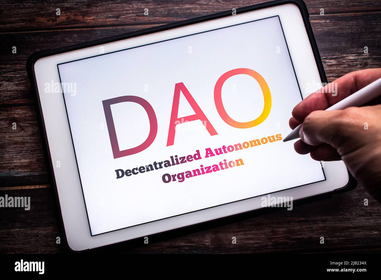 Sign of DAO (decentralizzata Autonomous Organization), un'organizzazione rappresentata da regole codificate come programma trasparente, su tablet. L'uomo tiene una penna Foto Stock