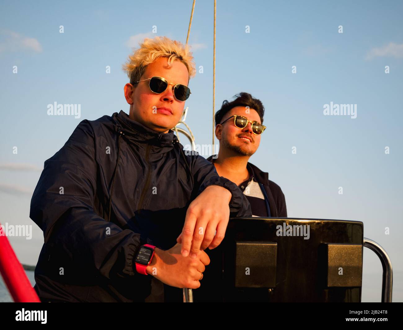 due persone su una barca a vela, una persona volante barca a vela altro è in piedi vicino a prua e guardando avanti al tramonto, vista frontale Foto Stock