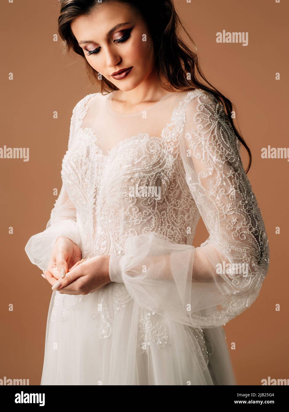 Giovane sposa in elegante abito da sposa in pizzo bianco con maniche lunghe trasparenti, decollette profonde e gonna a tulle lussureggiante. Primo piano ritratto candid Foto Stock