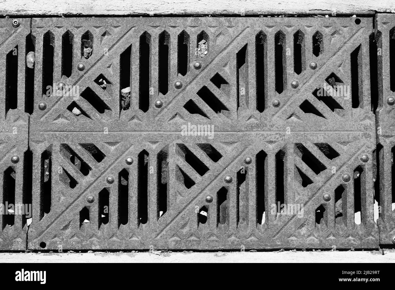 Coperchio di drenaggio delle fognature in bianco e nero standard in arrugginito. Foto Stock