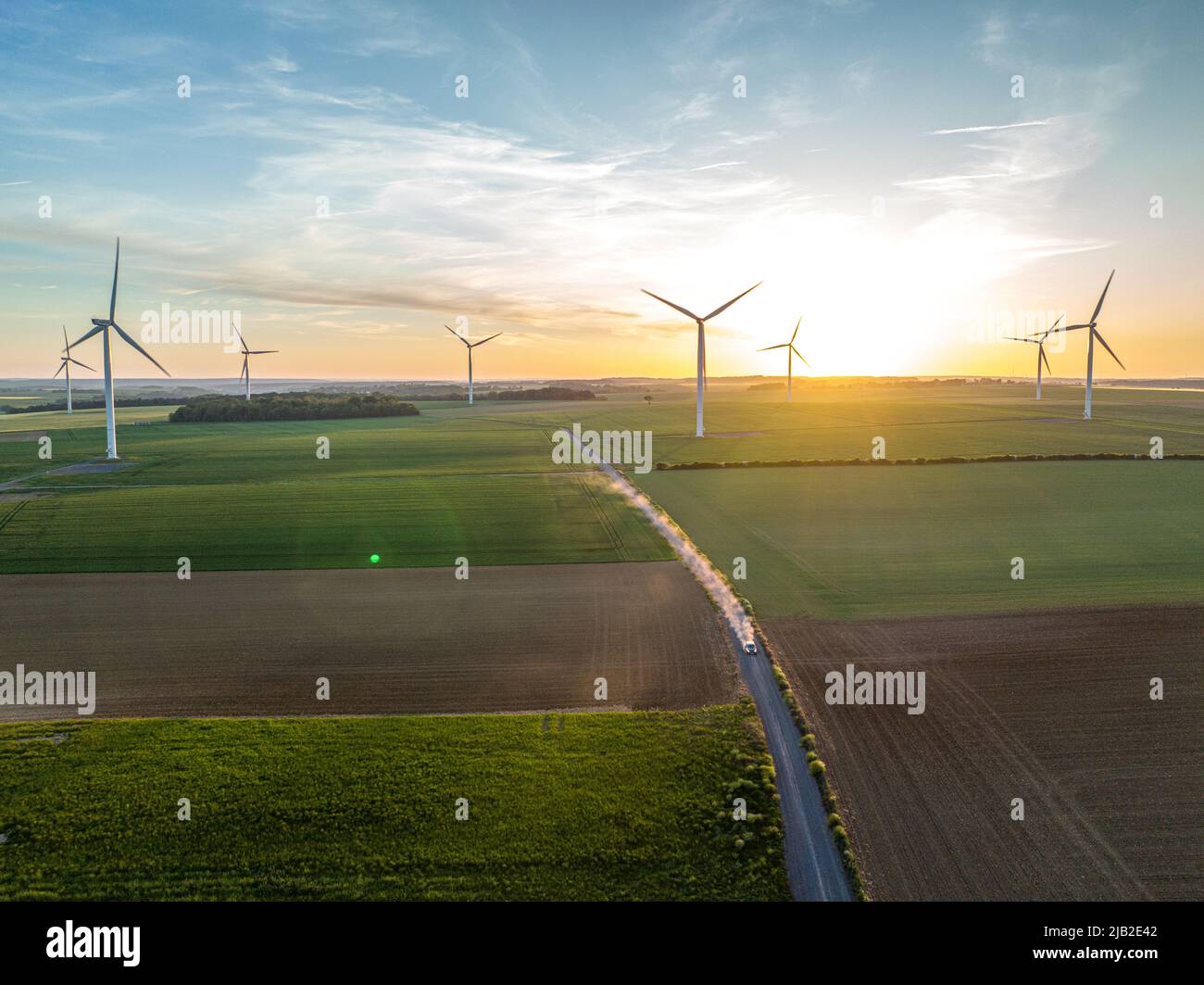 Ripresa aerea dall'alto in un tramonto, ci sono mulini a vento e un campo di colture. settore delle energie pulite e rinnovabili. Foto Stock