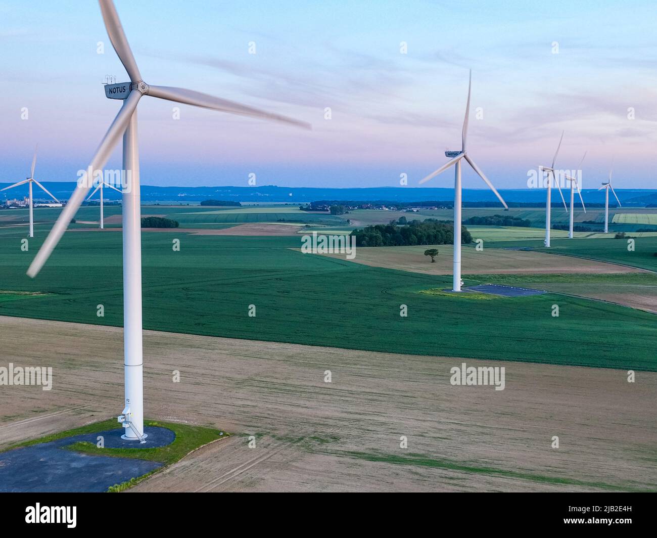 vista aerea di un parco eolico in un paesaggio lussureggiante che si estende ampiamente sotto un cielo limpido Foto Stock