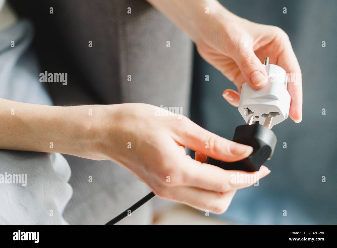 La donna applica l'adattatore universale per spina europea International AU UK US a Euro. Presa di alimentazione convertitore spina elettrica adattatore da viaggio Foto Stock